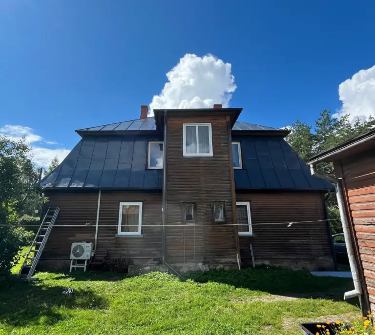 Metallist katusega maja katuse värvimise tulemus, et näidata katuse värvitööde efektiivsust maja eluea pikendamises. Pilt tehtud tööde hulgas.